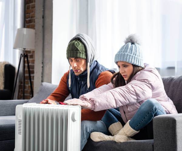 couple huddled up by residential space heater